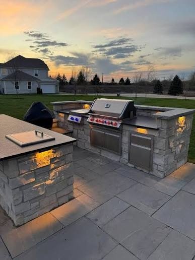 Stone outdoor kitchen with lighting at dusk