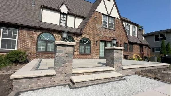 Raised front patio with stone pillars and steps on a Tudor home